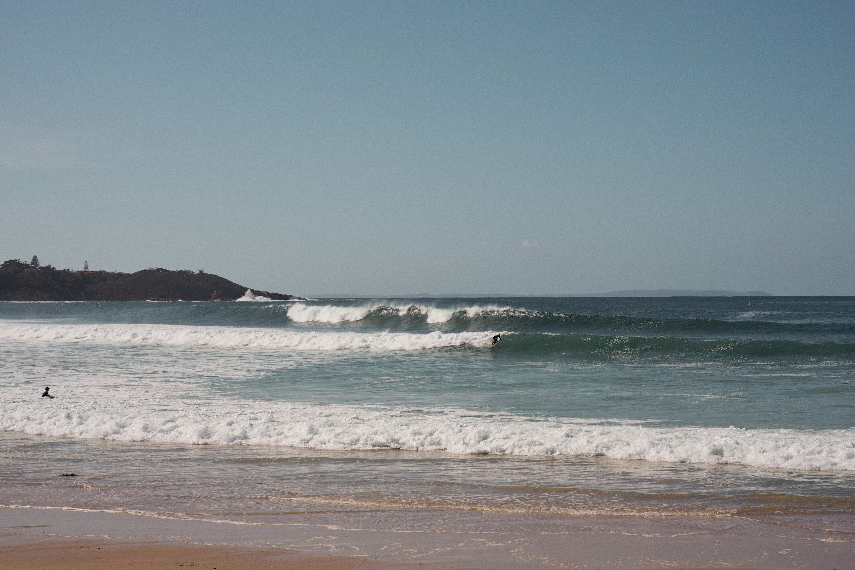 scenic beach view with gentle waves rolling onto the shore at Mollymook Beach.