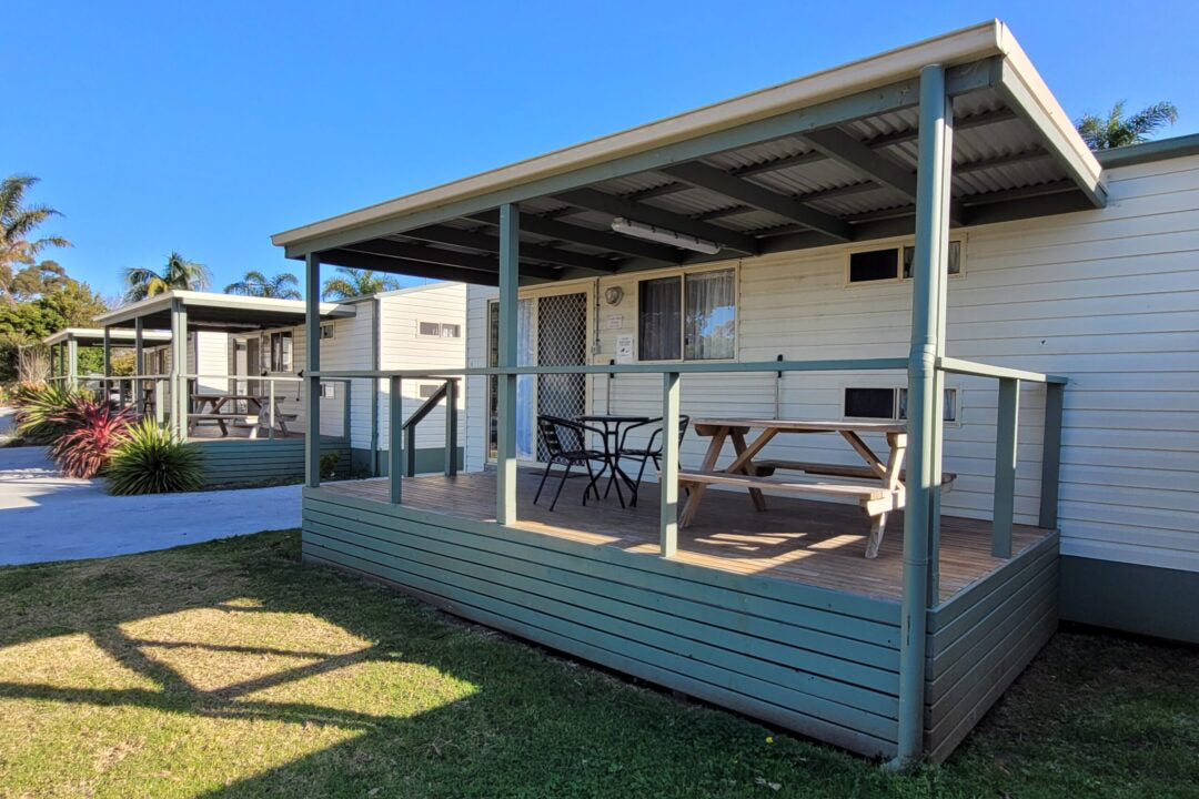 Covered deck with outdoor seating at Yerriyong A Cabin.