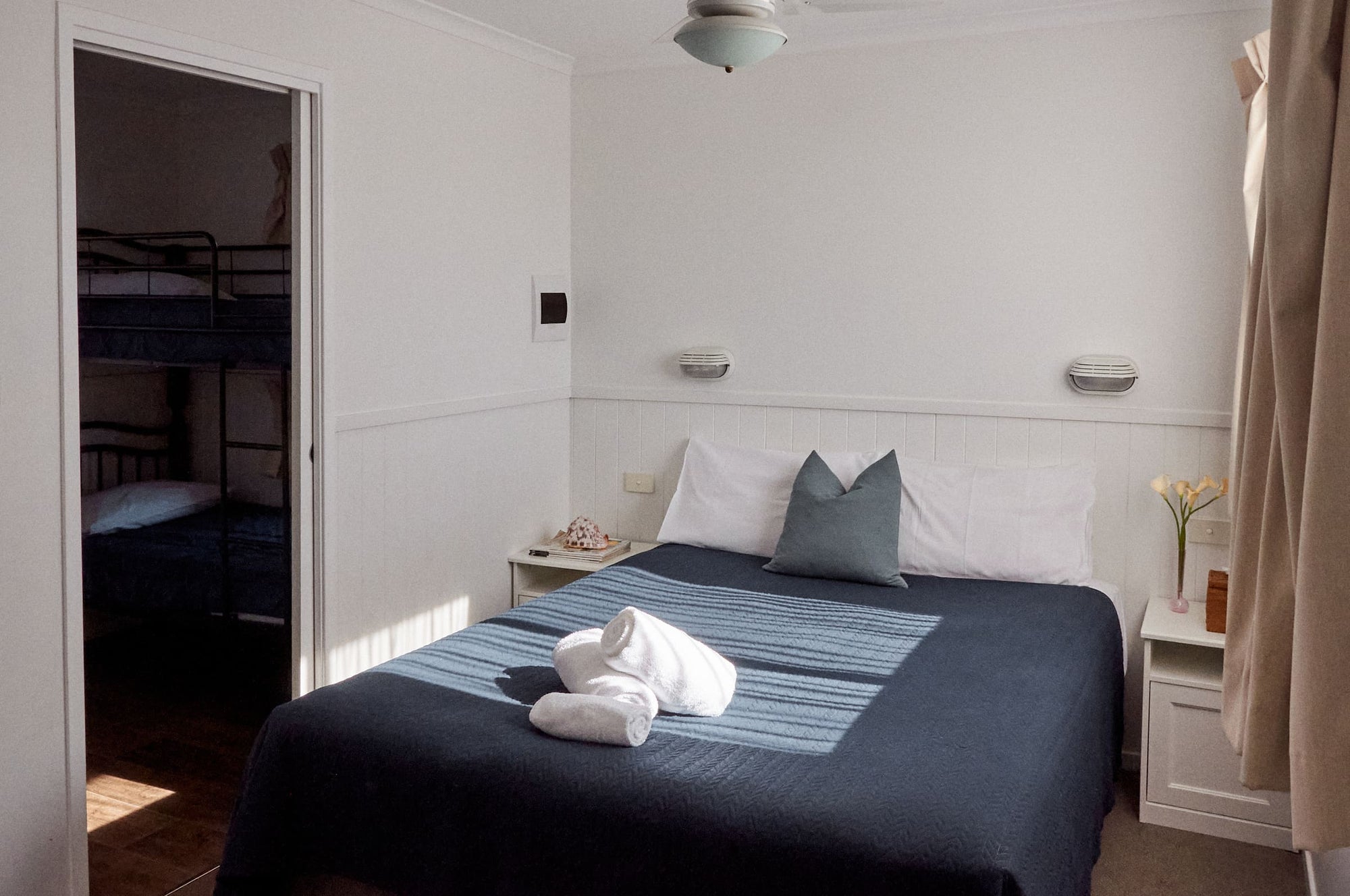 Main bedroom with queen bed and an open doorway revealing bunk beds in Morton A Cabin.