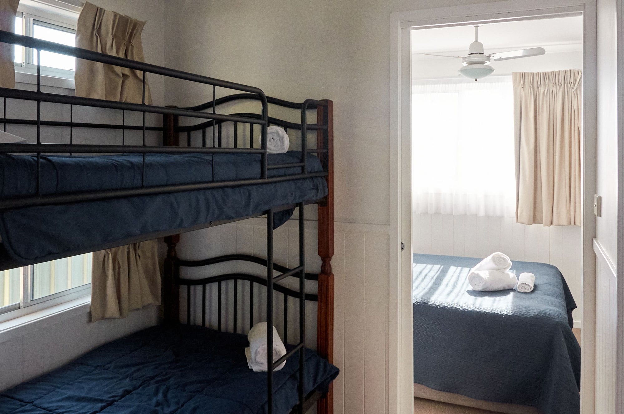 Second bedroom with a set of single bunk beds and an open doorway revealing queen bed in Morton A Cabin.